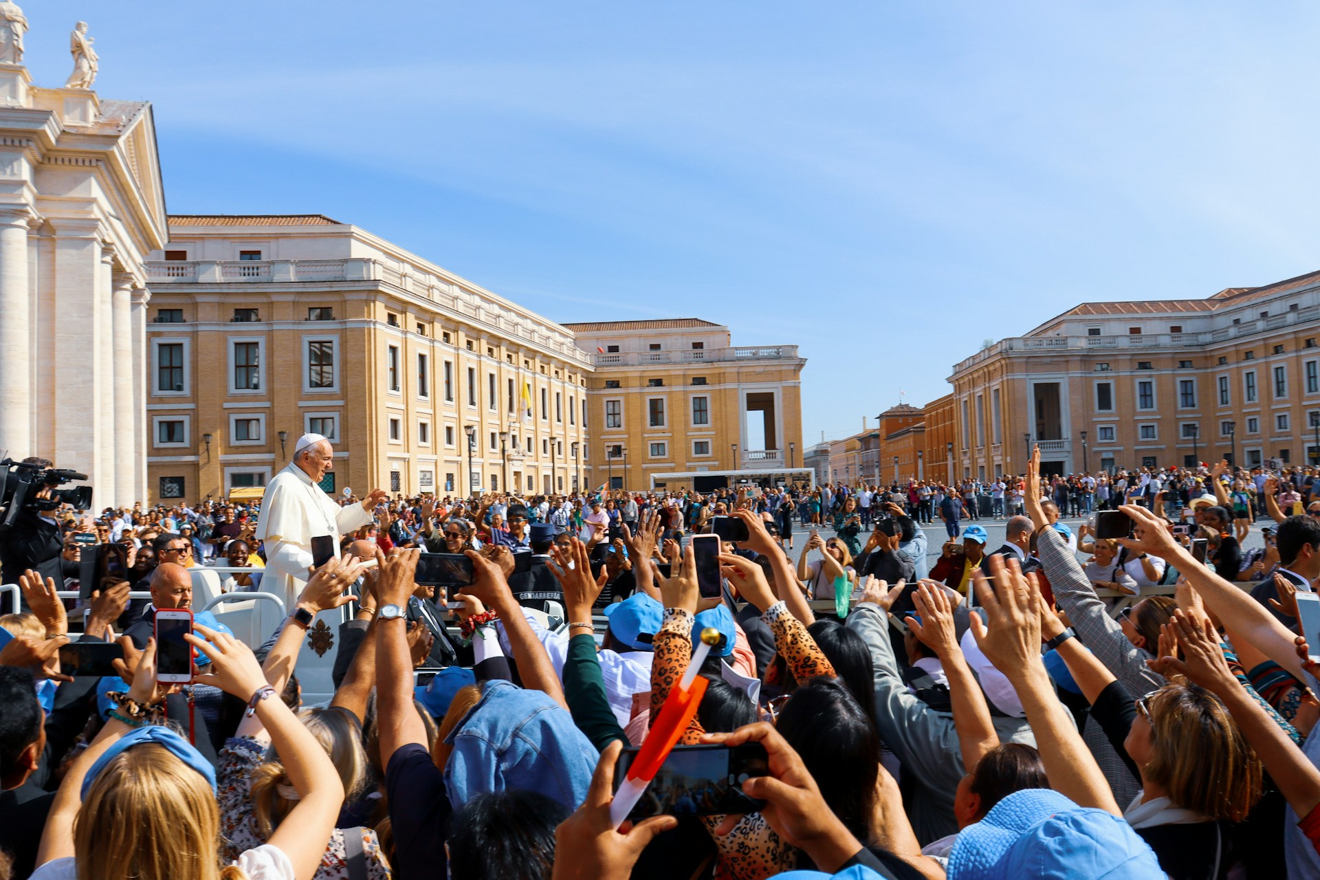 Crowd of people gathered in front of a cathedral with Pop Francis